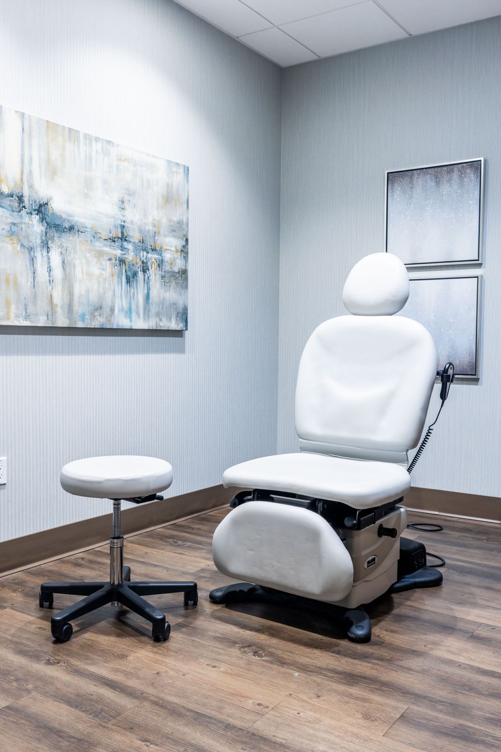 Medical examination room with white chairs and decor.