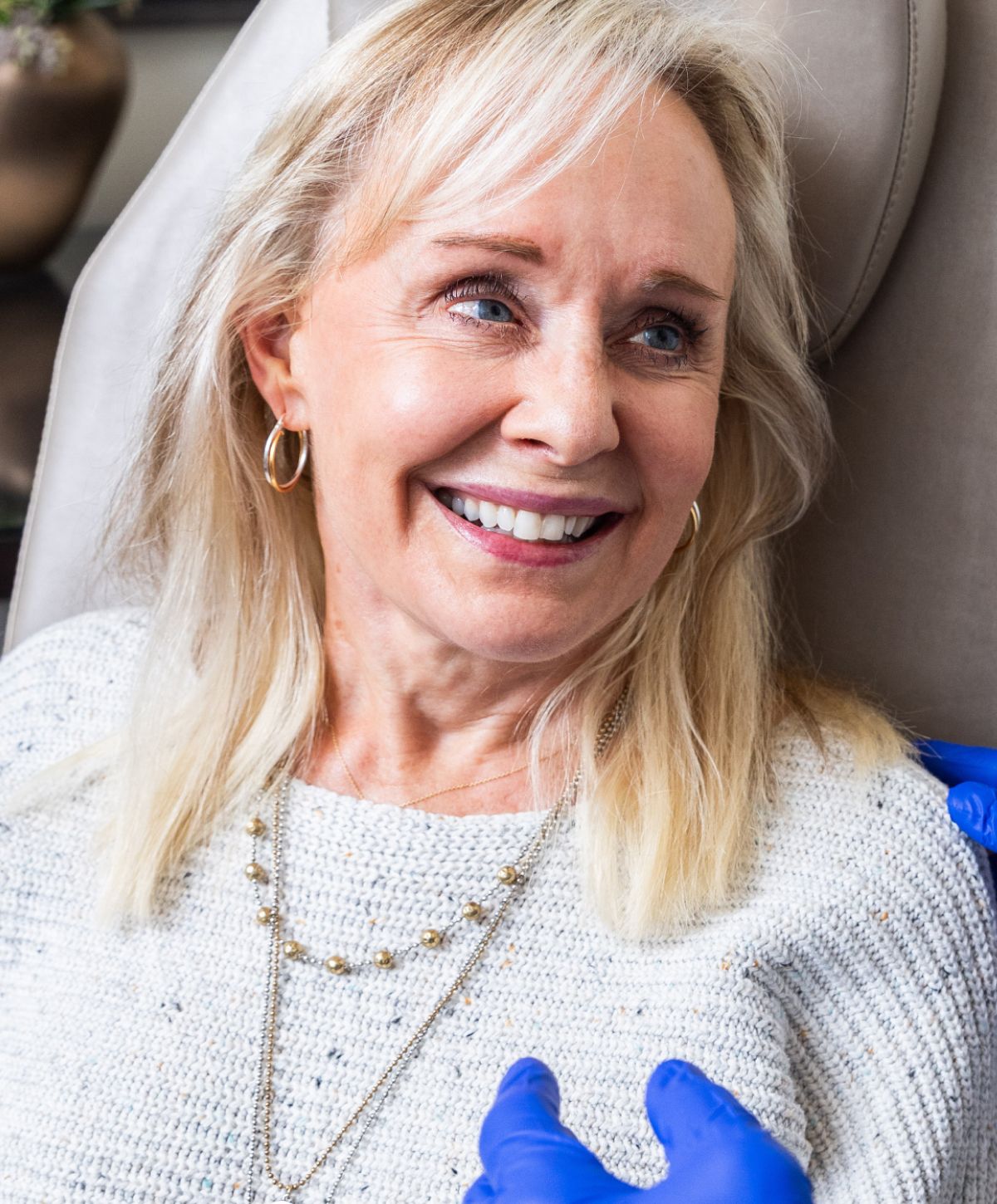 Smiling woman receiving facial treatment in clinic.